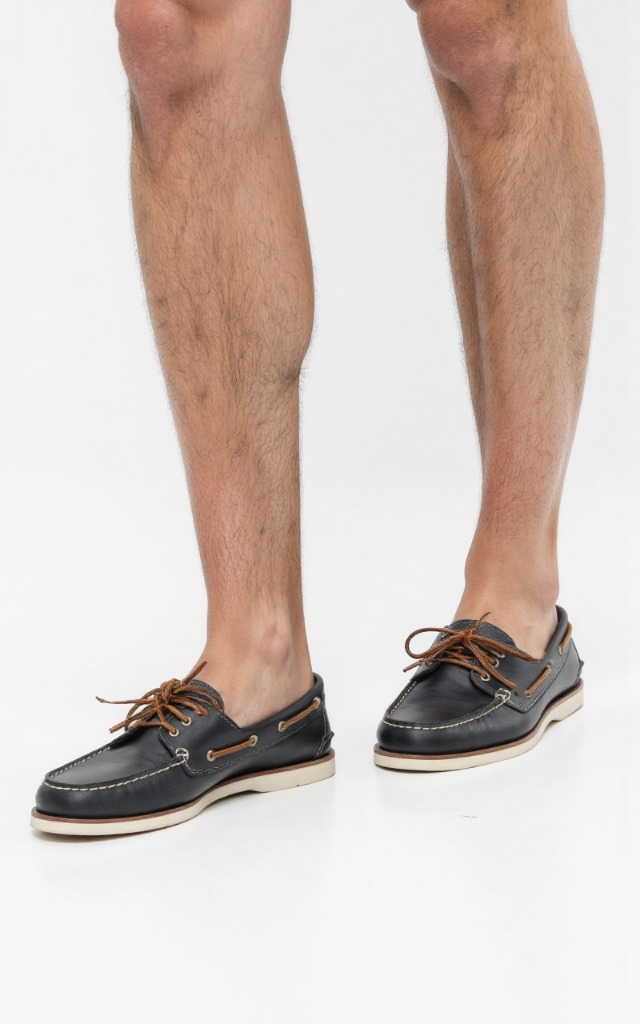 A male model wearing Boat shoes, against a white background, with a close   up of the feet